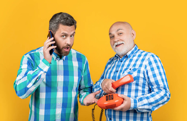 surprised men with telephone contrast call in studio. men with telephone contrast call on background. photo of men with telephone contrast call. men with telephone contrast call isolated on yellow. - Foto, immagini