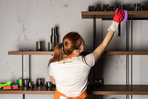 A woman in apron wipes furniture and shelves. microfiber cloth. Cleaning service. - Fotografie, Obrázek