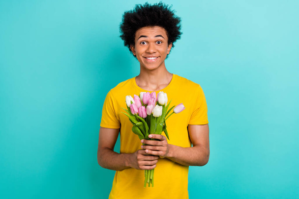 Photo de gai sympathique personne toothy sourire tenir bouquet fraîche fleurs de tulipe isolé sur fond de couleur turquoise. - Photo, image
