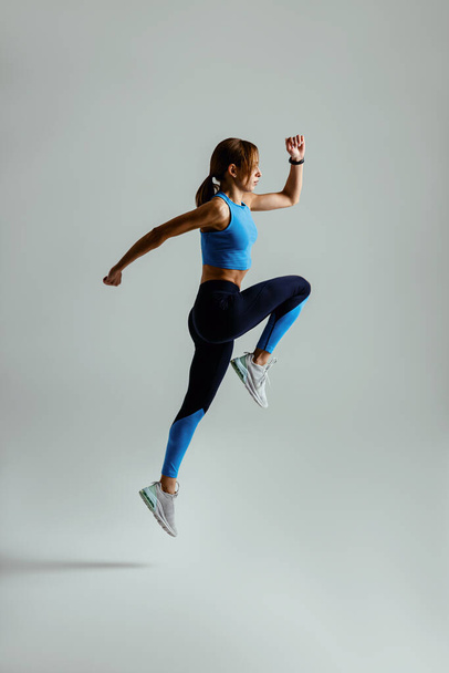 Žena běží ve vzduchu cvičení během kardio cvičení na pozadí studia. Kvalitní fotografie - Fotografie, Obrázek