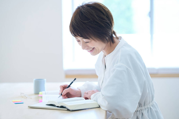 Жінка в свої тридцяті навчається за текстом у кімнаті
 - Фото, зображення