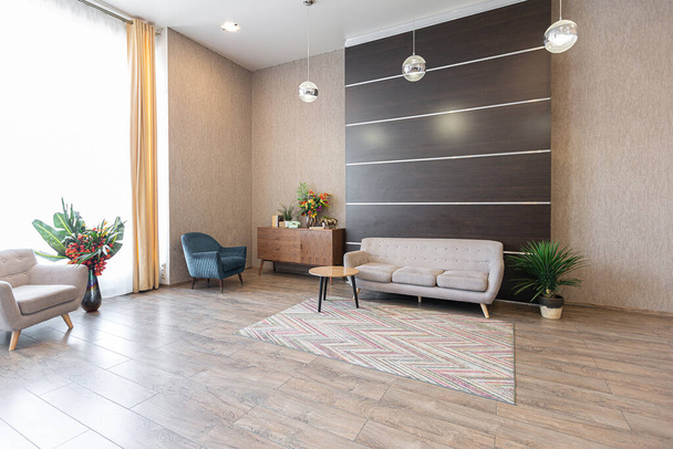 Contemporary ordinary design of spacious studio in soft warm colors. Simple furniture. Light large room with sunlight. Daytime. Tiled brown floor and white walls . - Fotoğraf, Görsel