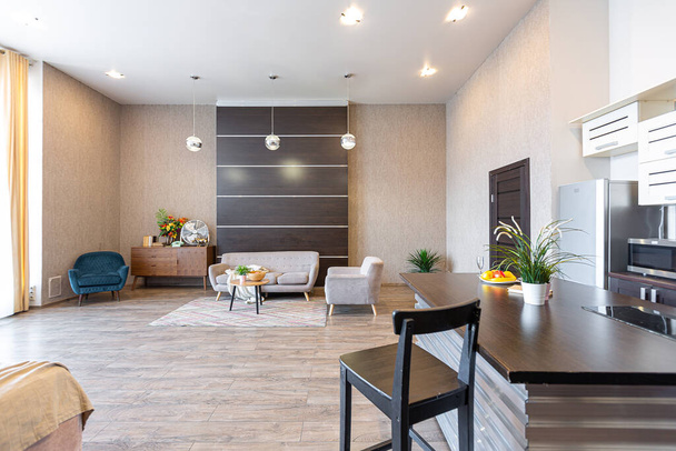 Contemporary ordinary design of spacious studio in soft warm colors. Simple furniture. Light large room with sunlight. Daytime. Tiled brown floor and white walls . - Foto, Imagem