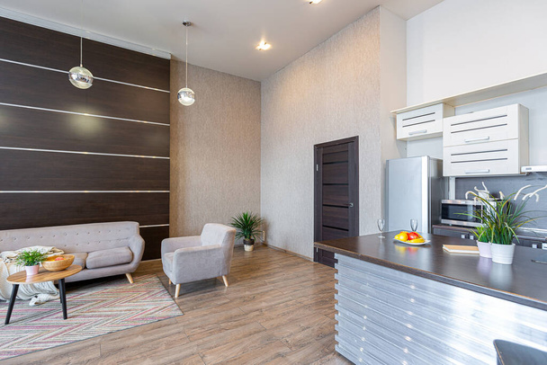 Contemporary ordinary design of spacious studio in soft warm colors. Simple furniture. Light large room with sunlight. Daytime. Tiled brown floor and white walls . - Fotó, kép