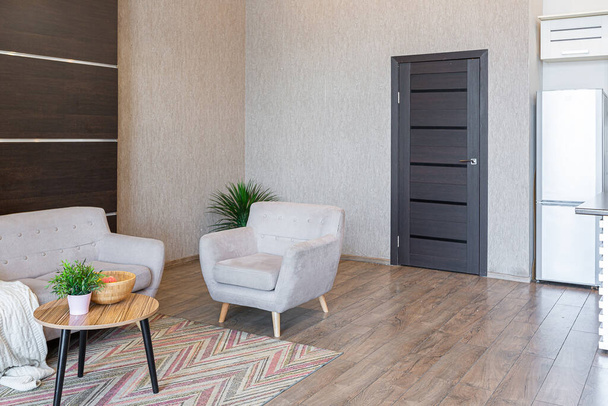 Contemporary ordinary design of spacious studio in soft warm colors. Simple furniture. Light large room with sunlight. Daytime. Tiled brown floor and white walls . - Valokuva, kuva