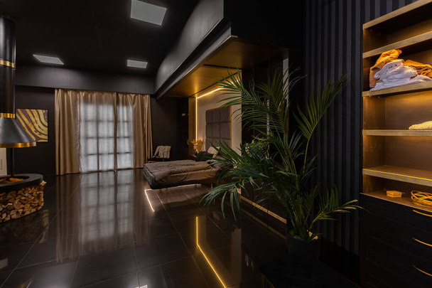 dark modern stylish male apartment interior with lighting, decorative walls, fireplace, dressing area and huge window - Fotó, kép
