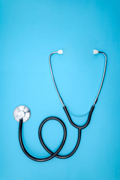 Stethoscoop op een blauwe achtergrond. Cardiologie concept, close-up bovenaanzicht, verticaal - Foto, afbeelding