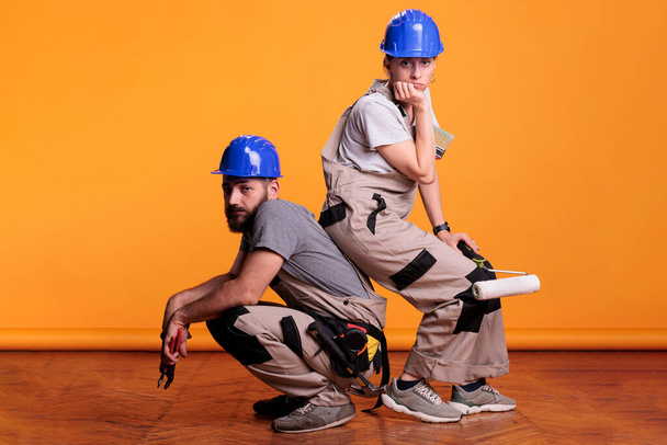 Professional carpenters holding construction tools in studio shot, posing with working instruments. Team of constructors working with pair of pliers, painting roller and brush over background. - Foto, immagini