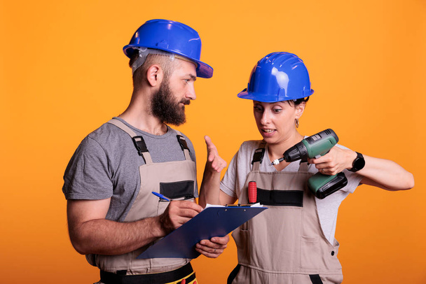 Tým inženýrů se dívá na stavební měření na deskách, drží papíry a elektrickou vrtačku. Dodavatelé hovoří o renovaci projektu, přípravě na rekonstrukci. - Fotografie, Obrázek