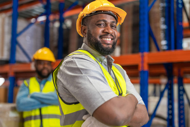 Trabajadores varones africanos que usan ropa de trabajo y cascos de seguridad en el almacén de la fábrica industrial. Control de calidad de la inspección. - Foto, Imagen