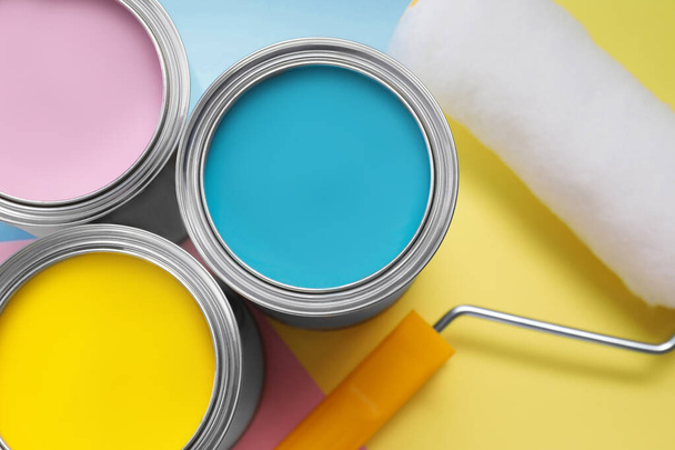 Cans with different paints and roller on color background, flat lay - Photo, Image