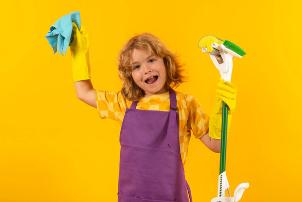 Kind helpt met schoonmaken. Kind schoonmaken met dweil om te helpen met huishoudelijk werk. Kleine schattige jongen vegen en schoonmaken, geïsoleerd op studio kleur achtergrond - Foto, afbeelding