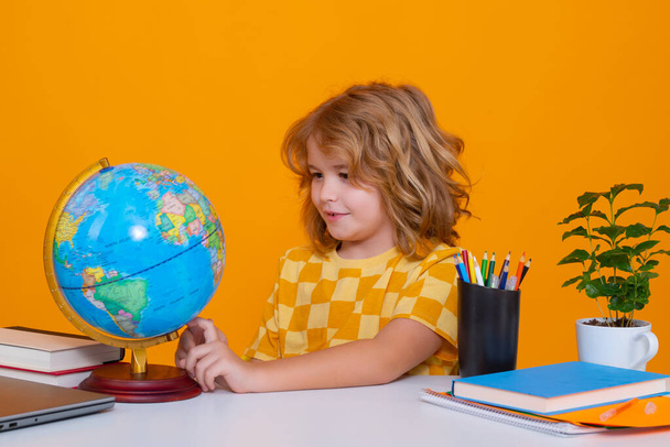 School child studying in classroom at elementary school. Kid studying on lesson looking at globe during geography lesson at elementary school - Fotografie, Obrázek