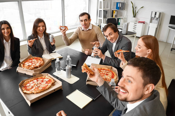 Gruppe von Geschäftsleuten mit leckerer Pizza im Büro - Foto, Bild