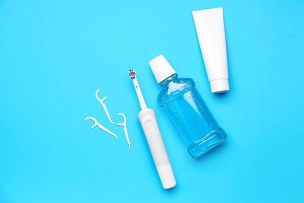 Floss toothpicks, electric brush, paste and rinse on blue background - 写真・画像