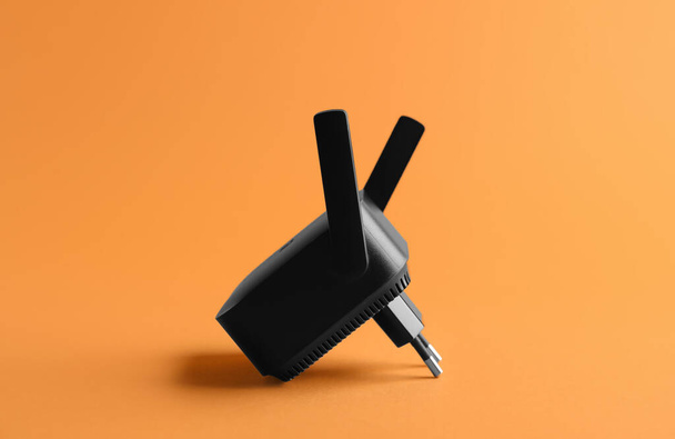Schwarzer WiFi Repeater auf orangefarbenem Hintergrund - Foto, Bild
