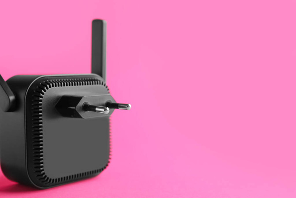 Schwarzer WiFi-Repeater auf rosa Hintergrund - Foto, Bild