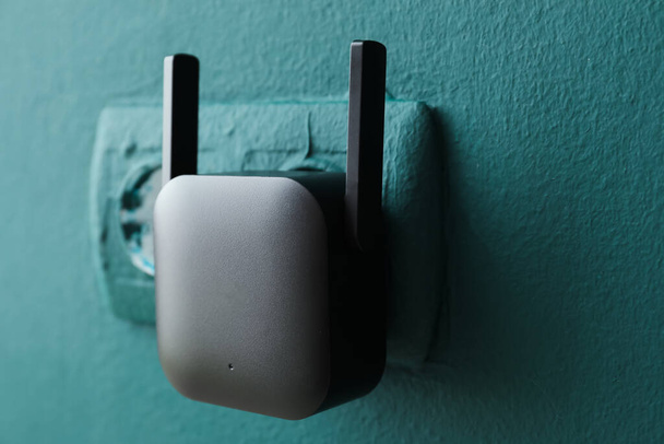 Repetidor WiFi negro en toma eléctrica en pared verde - Foto, imagen
