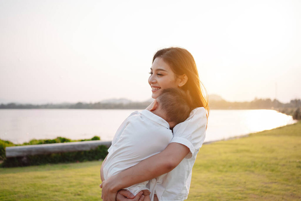 Mother Parenting and newborn birth life. Mom and baby boy playing in park sunset, Family having fun together. childcare, maternity concept. - Фото, изображение