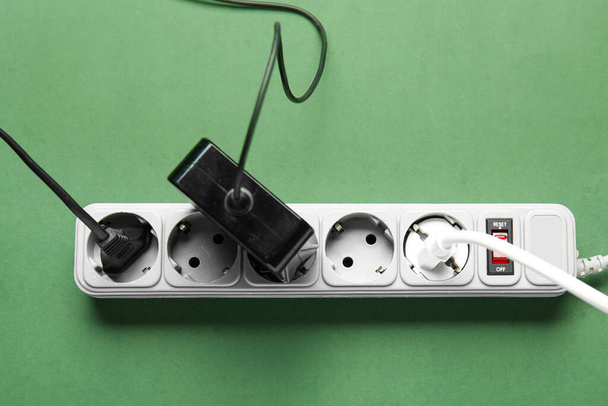 Electric extension cord with plugs on green background - Fotó, kép