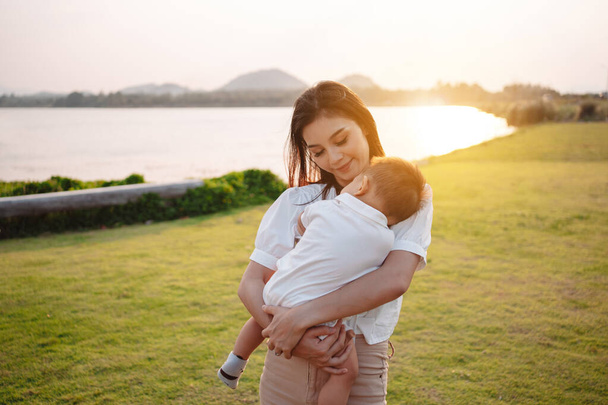 Mother Parenting and newborn birth life. Mom and baby boy playing in park sunset, Family having fun together. childcare, maternity concept. - Foto, Imagen
