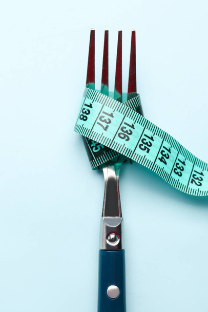 Measuring tape and fork on blue background - Fotó, kép