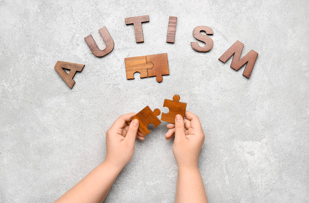 Слово AUTISM і дитина з шматочками головоломки на гранжевому фоні
 - Фото, зображення