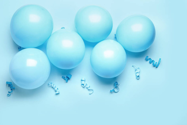 Μπλε μπαλόνια, κορδέλες και φιόγκο σε φόντο χρώματος - Φωτογραφία, εικόνα