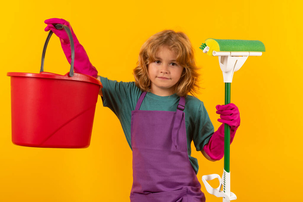 Lapset auttavat siivoamisessa ja siivoamisessa. Siivooja kotona. Söpö lapsi poika auttaa taloudenhoito keltainen studio backdround - Valokuva, kuva