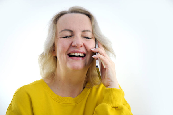 Portrait of attractive cheerful grey-haired woman sitting on divan talking on phone cellular at home house flat indoors. High quality photo - Фото, изображение