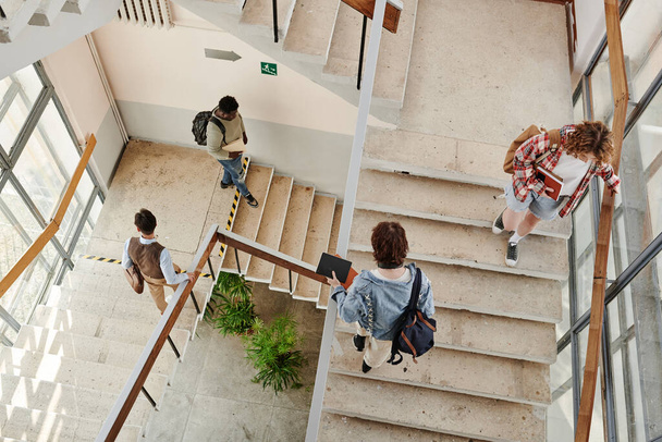 Overview of teenage students going up and down staircase in corridor while leaving for home or another university building - Fotoğraf, Görsel