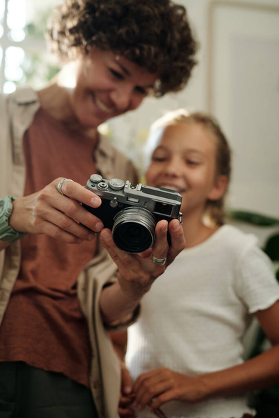 Manos de mujer joven sosteniendo la cámara fotográfica y mostrando nuevas fotos a su hija joven después de disparar en el ocio - Foto, Imagen