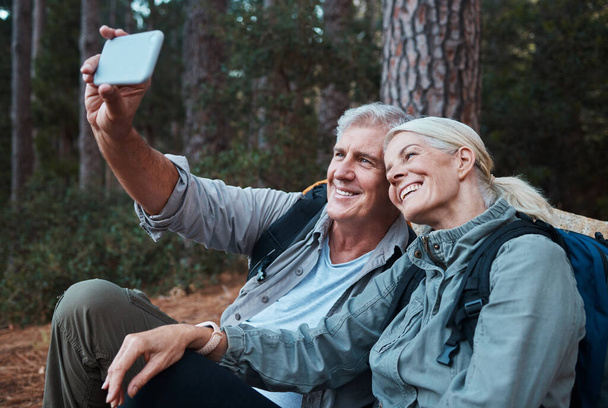 Senior couple, selfie and hiking in forest, happy people in nature with memory and social media post. Smile in picture, adventure and fitness, old man and woman with active lifestyle and outdoor. - Foto, immagini