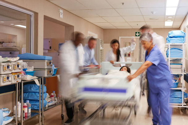 Ścigają się, by uratować pacjenta. zespół medyczny pędzący nosze korytarzem szpitalnym - Zdjęcie, obraz