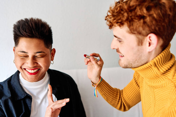 Portrait of a happy gay couple having fun while applying make up at home - Photo, image