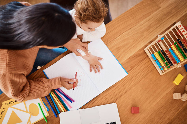 Learning, top view and mother with kid drawing in book in family home for studying, homework or homeschool help. Creative development, art and boy with mom teaching him art for education child growth. - Photo, image
