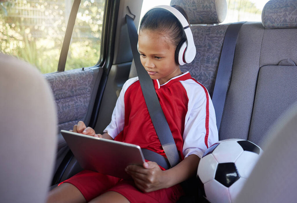 Tablet, spor ve rahat çocuk futbol, futbol ya da maç için emniyet kemeri takılı SUV minibüste araba yolculuğunda. Genç kız videosu, abonelik filmi ya da çocuk dostu uygulama kullanın. - Fotoğraf, Görsel