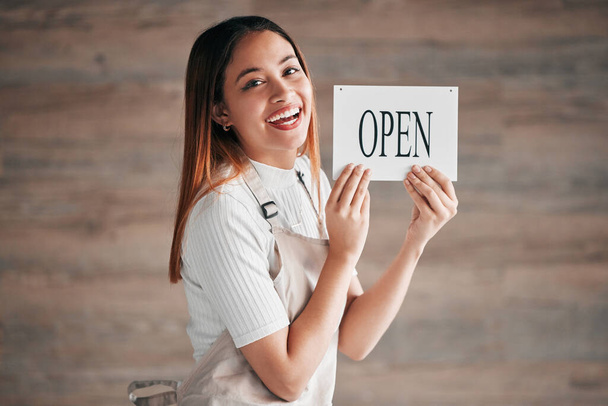 Coffee shop, portrait and woman holding an open sign in studio on a blurred background for hospitality. Cafe, startup and management with a female owner or entrepreneur indoor to display advertising. - Foto, Imagem