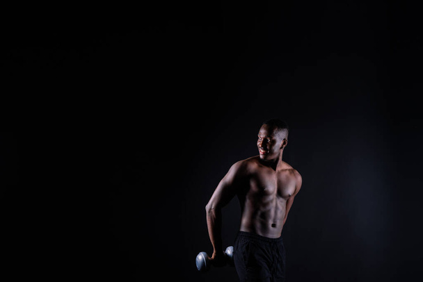 Portrait of happy african man with dumbbells over red and black background - Foto, Imagem