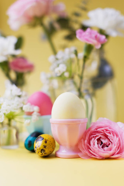 Easter eggs and flowers on a yellow background. Easter background with pastel colors details. Spring holiday concept - 写真・画像