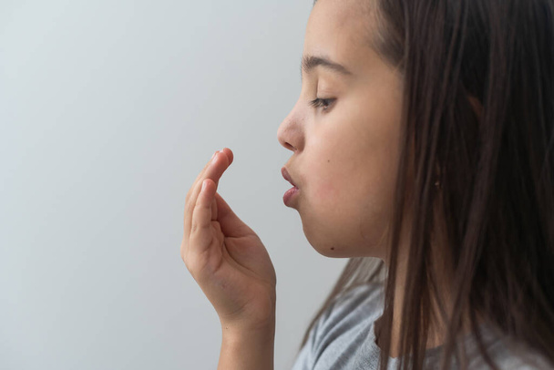 Klein Aziatisch meisje bedekt haar mond om haar slechte adem te ruiken. Orale gezondheidsproblemen. Tandheelkundige gezondheidszorg - Foto, afbeelding