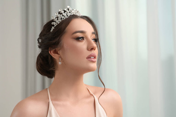 Beautiful young woman wearing luxurious tiara indoors, space for text - Foto, Bild