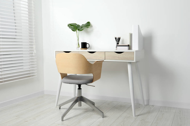 Comfortable workplace with white desk near wall indoors - Fotó, kép