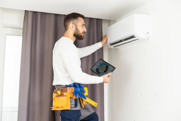 Mies teknikko korjaus ilmastointilaite sisätiloissa
 - Valokuva, kuva