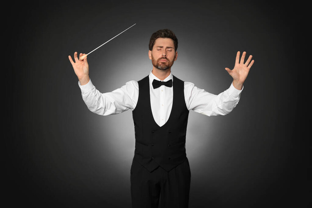 Professional conductor with baton on black background - Фото, зображення