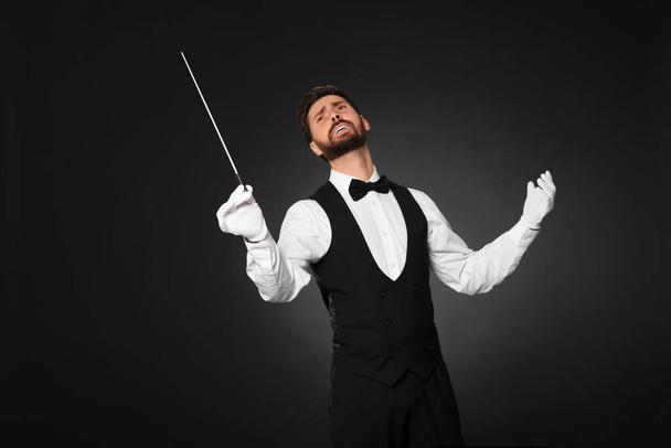 Professional conductor with baton on black background - Foto, Imagen