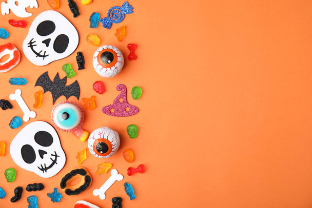 Tasty candies and Halloween decorations on orange background, flat lay. Space for text - Fotoğraf, Görsel