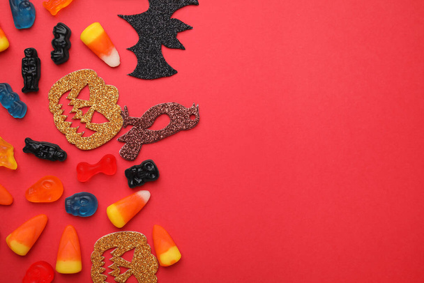 Tasty candies and Halloween decorations on red background, flat lay. Space for text - Fotoğraf, Görsel