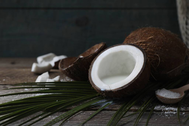 Coconut milk, flakes, nuts and palm leaf on wooden table, space for text - Zdjęcie, obraz