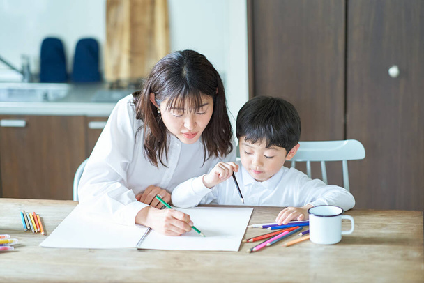 Mãe e filho estudando com lápis e caderno na sala - Foto, Imagem
